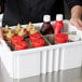 A gray Long Metro tote box divider holding white containers of ketchup and mustard on a counter.