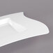 A close-up of a white Fineline square plate with a curved edge.