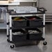 A black Cambro utility cart with trays on it.