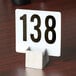 A stainless steel American Metalcraft box style table card holder with a white card with black number 13 on it.
