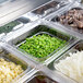 A Turbo Air 2 door refrigerated sandwich prep table with trays of food on a counter in a salad bar.