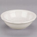 A CAC ivory scalloped edge fruit dish on a gray surface.