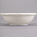 A white bowl with a scalloped edge on a gray surface.