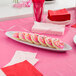A white oval platter with frosted cookies on a table with a pink tablecloth.