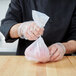 A person in a chef's uniform holding a LK Packaging plastic bag of food.