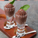 Two Libbey spirit shot glasses of chocolate pudding with mint leaves on top.