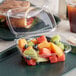 A Dart ClearPac plastic container filled with fruit and sandwiches.