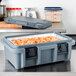 A Cambro Granite Gray food pan carrier on a table with food inside.