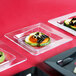Fineline clear plastic square trays with food on them.