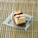 A piece of cheesecake on a Fineline clear plastic square tray.