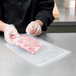 A person in gloves using an ARY VacMaster chamber vacuum packaging bag to pack a piece of meat.
