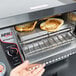 A person using an APW Wyott conveyor toaster to make toast.
