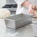 A person kneading dough in a Chicago Metallic aluminized steel bread loaf pan.