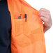 An XL Cordova orange high visibility safety vest with pockets and a pen pocket being put on.
