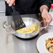 A chef using a Vollrath Miramar French omelet pan to cook eggs.