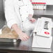 A chef using a Tablecraft KenKut film and foil dispenser to cover a container of food.