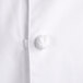 A close up of a white Chef Revival chef jacket with cloth knot buttons.