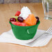 A green Thunder Group melamine bowl filled with fruit and whipped cream on a counter.