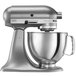 A silver KitchenAid Artisan stand mixer with a bowl attached.