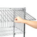 A hand pulling a Metro Super Erecta wire security shelf.