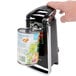 A hand using a Hamilton Beach electric can opener to open a can of food.