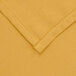 A close up of a yellow rectangular table cover with hemmed edges.