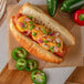 A hot dog with Muy Fresco Jalapeno Nacho Cheese Sauce, cheese, and jalapenos on a counter.