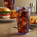 A blue GET Bahama plastic tumbler filled with cola and ice next to a burger on a table.