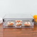 A Cal-Mil stackable acrylic display case with pastries and oranges on a tray.
