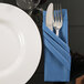 A fork and knife in a navy blue linen-like napkin.