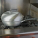 A Vollrath SteelCoat x3 Non-Stick Aluminum Stir Fry Pan on a stove.