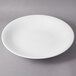 A 10 Strawberry Street white porcelain coupe bowl with a white rim on a gray surface.