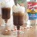 A glass of brown liquid with white foam and a straw on the side, made with Torani White Chocolate Flavoring Syrup.