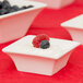 A white Arcoroc flared bowl filled with blueberries and raspberries.