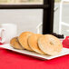 A rectangular white porcelain platter with bagels and a cup of coffee.
