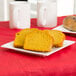 An Arcoroc porcelain side plate with pumpkin bread on a table with two white mugs.