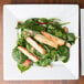 An Arcoroc porcelain brunch plate with salad, chicken, and spinach.