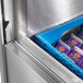 A Traulsen school milk cooler with blue and purple boxes inside.