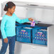 A girl opening a Traulsen milk cooler in a school kitchen.