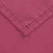 A close up of a mauve rectangular poly/cotton table cover with hemmed edges.