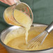 A person using a whisk to stir Regal unsweetened applesauce.