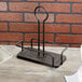 A black metal Tablecraft Marbella rack with two metal rods on a wood surface.