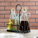 A Tablecraft Marbella metal rack with glass containers holding oil and vinegar.