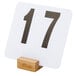 A curved natural bamboo table card holder with a white card and black numbers.