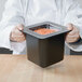 A chef holding a Cambro black food pan filled with carrots.