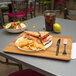 A Carlisle Glasteel Butcher Block tray with sandwiches and chips on a table.