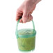 A hand holding a jade green GET Reusable Eco-Takeout soup container with a lid.