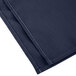 A folded navy blue Intedge cloth napkin with white stitching.