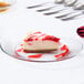 A slice of cheesecake with strawberries on top on a Libbey glass plate.