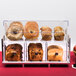 A Cal-Mil modern merchandiser display case on a bakery counter filled with different types of bread.